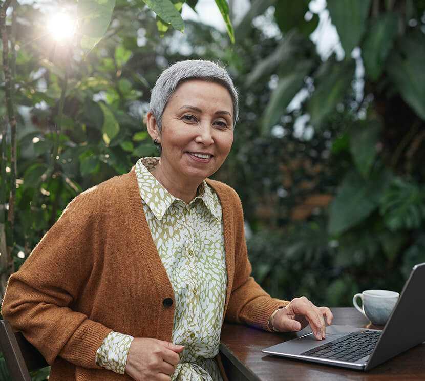 Mature senior woman smiling while using laptop
