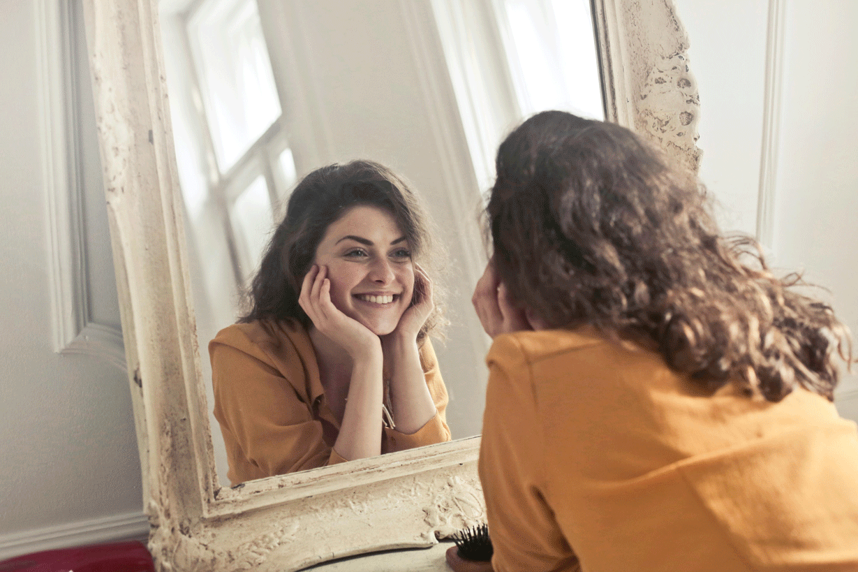 happy women looking in mirror after completing our transcranial magnetic stimulation therapy in Arizona