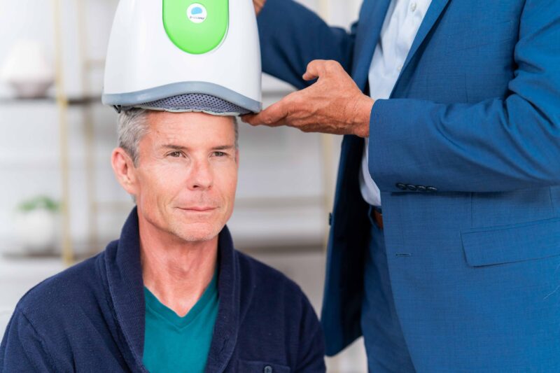 Clinician positioning a BrainsWay device on a patient’s head during a session, demonstrating TMS treatment for OCD