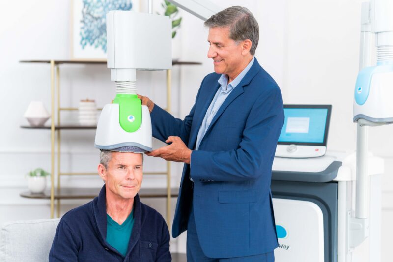Clinician positioning a BrainsWay TMS device on a patient during a session, demonstrating TMS treatment for addiction