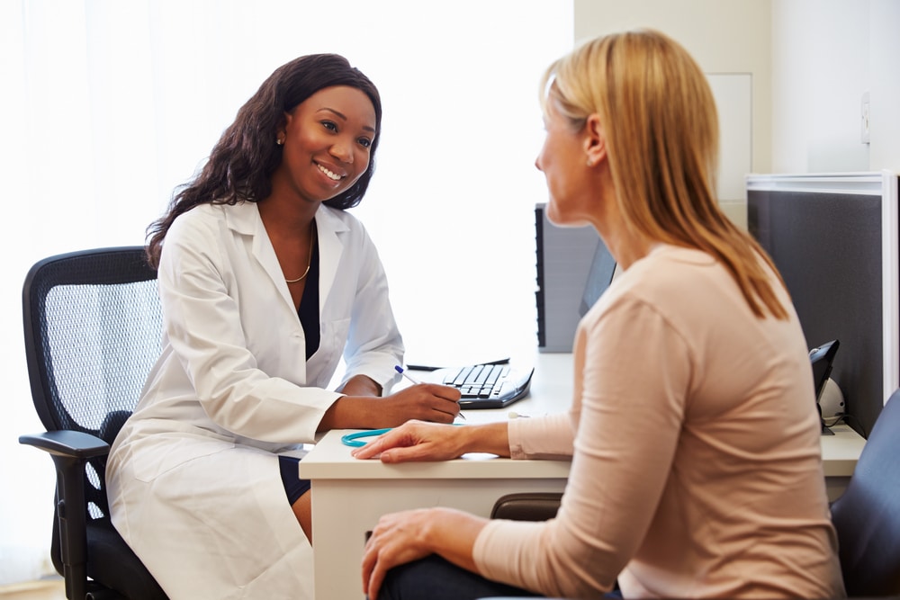 Professional consulting with a patient in a clinical office, discussing Transcranial Magnetic Stimulation for anxiety treatment options