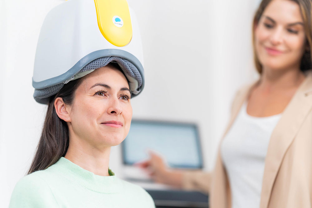 Woman receiving a brain stimulation session, illustrating Transcranial Magnetic Stimulation for process addictions