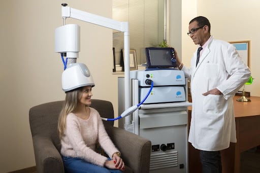 Seated patient engaging with a clinician during a session designed to support TMS for brain performance enhancement